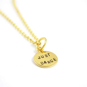 May include: Gold necklace with a round pendant that says "JUST DANCE" in black lettering.