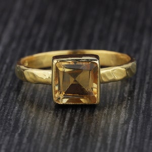 Peut inclure: Une bague en or avec une pierre précieuse carrée de couleur brun clair.