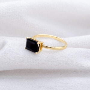 May include: A gold ring with a black emerald-cut gemstone.