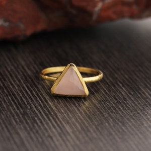 May include: A gold ring with a triangular pink gemstone.