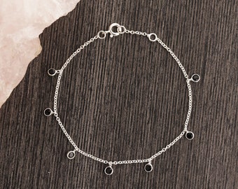 Peut inclure: Un bracelet en chaîne argent avec des accents de pierres précieuses noires. Le bracelet a une fermeture à fermoir et présente un design de chaîne délicat.