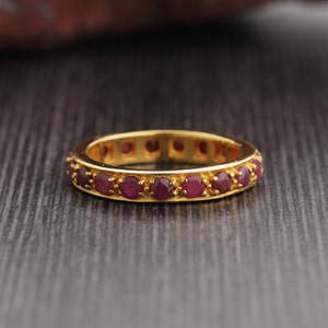 Peut inclure: Une bague en or avec une rangée de petites pierres précieuses rondes rouges.