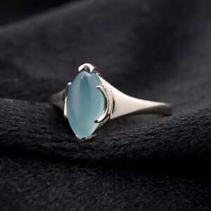 May include: A silver ring with a light blue oval-shaped gemstone.