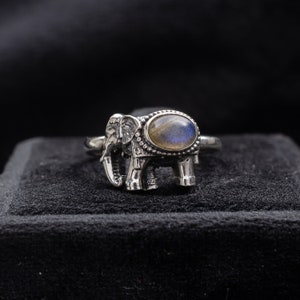 Può includere: Un anello d'argento con un design a forma di elefante e una pietra preziosa blu-verde al centro.