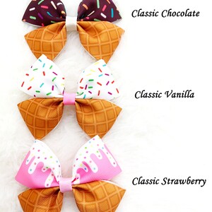 May include: Three ice cream cone hair bows with different flavors: chocolate, vanilla, and strawberry. Each bow features a waffle cone pattern and a colorful ice cream design.