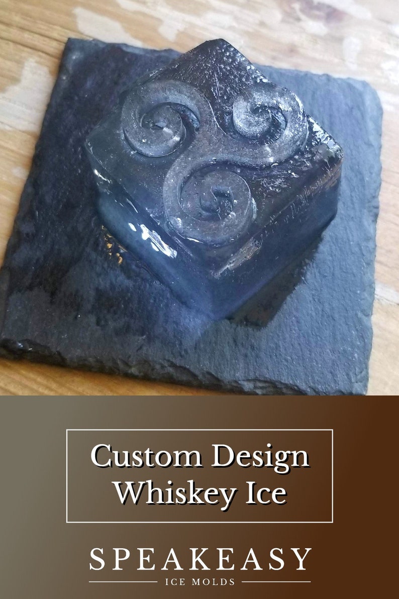 May include: A clear ice cube with a swirling design on a black slate coaster. The ice cube is a custom design whiskey ice mould. The text "SPeakeasy Ice Molds" is below the ice cube.