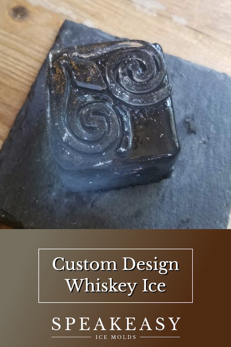 May include: A clear ice cube with a swirling design, resting on a black slate surface. The ice cube is labelled "Custom Design Whiskey Ice" and "Speakeasy Ice Molds".
