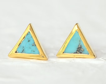 Könnte beinhalten: Ein Paar goldfarbene Dreiecks-Ohrstecker mit türkisfarbener Steineinlage. Die Ohrringe haben ein geometrisches Design und sind vor einem weißen Hintergrund platziert. Der Türkisstein hat ein gesprenkeltes Aussehen.
