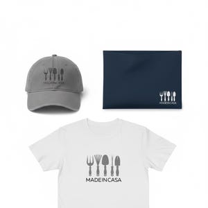 Puede incluir: Una gorra de béisbol gris, un estuche rectangular azul oscuro y una camiseta blanca. Cada artículo presenta un gráfico de cuatro herramientas de jardinería y el texto "MADEINCASA" impreso con un estilo coherente en las tres piezas.