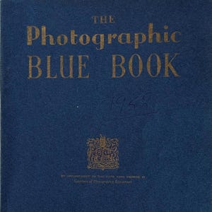 Op de afbeelding: Een vintage blauw boek met de titel "The Photographic Blue Book" met gouden letters. De omslag bevat de tekst "Wallace Heaton Ltd" en het adres 127 New Bond Street, Londen, W.1.