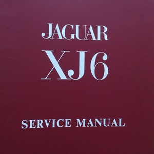 May include: A maroon Jaguar XJ6 service manual. The cover displays "JAGUAR XJ6" in white, with "SERVICE MANUAL" underneath. The publication number, E.155, is printed at the bottom.