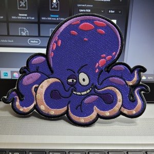Peut inclure: Une pieuvre violette avec un sourire malicieux et des taches roses. La pieuvre a huit tentacules avec des rayures blanches et violettes. La pieuvre est un patch en feutre.