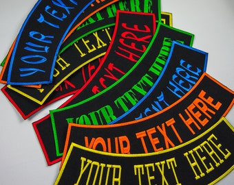May include: A stack of black fabric patches with curved edges. The patches have different coloured embroidered text that reads "YOUR TEXT HERE".