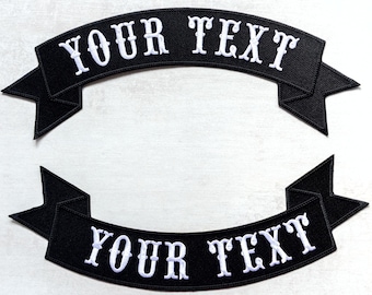 May include: Two black embroidered banner patches with white text that reads "YOUR TEXT". The patches are curved with pointed ends, suitable for customisation on jackets or bags. The patches are on a white surface.