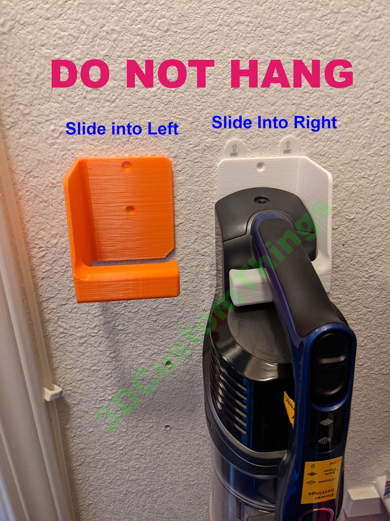May include: A white wall mount with the text "DO NOT HANG" in pink letters. The wall mount is designed to hold a cordless vacuum cleaner. The vacuum cleaner is blue and black and is partially visible in the image. The text "Slide into Left" and "Slide into Right" are written in blue letters below the wall mount.