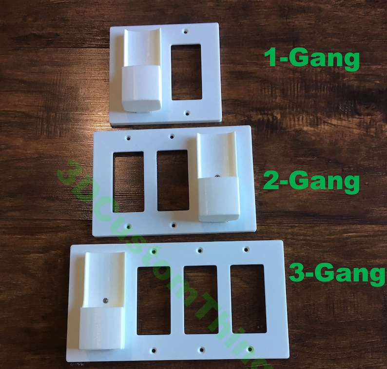 May include: Three white plastic electrical outlet covers with a built-in phone or tablet holder. The covers are labeled 1-Gang, 2-Gang, and 3-Gang.