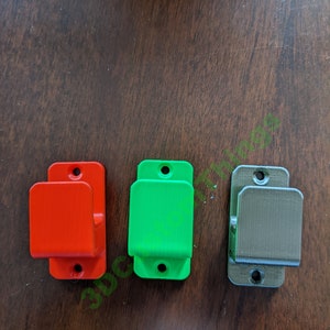 Puede incluir: Tres ganchos de pared en rojo, verde y gris. Los ganchos son de plástico y tienen un diseño sencillo.