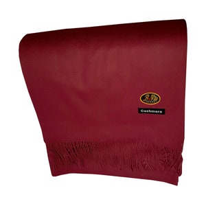 Peut inclure: Une écharpe en cachemire bordeaux avec une bordure à franges et une petite étiquette indiquant "B-Vito Cashmere".