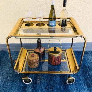 Een zeldzame Art Deco-barwagen uit de jaren twintig van goudkleurig messing met twee glazen etages op rubberen wielen.