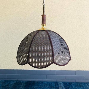 Puede incluir: Lámpara colgante con pantalla tejida en forma de campana. La pantalla es de color marrón oscuro con un borde festoneado. La lámpara tiene una base de latón y un acento de madera. Una cadena blanca suspende la luz del techo.