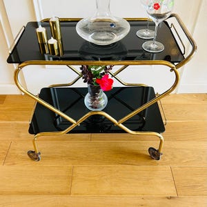 アールデコ調の 1930 年代の金色のバー カート。真鍮製で、ゴム製の車輪に 2 段のガラスが付いています。