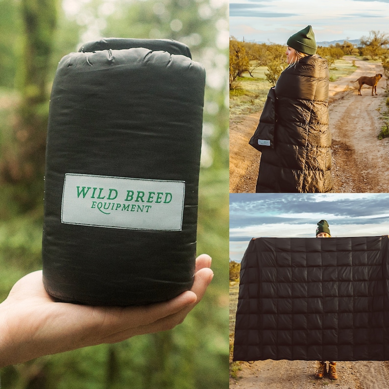 May include: A black down blanket with a quilted pattern. The blanket is folded and held by a person's hand. The blanket has a green label that says "WILD BREED EQUIPMENT".