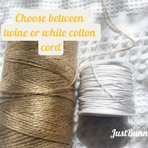Op de afbeelding: Twee spoelen touw, een bruin en een wit. De bruine spoel is ge&euml;tiketteerd "twine" en de witte spoel is ge&euml;tiketteerd "white cotton cord". De tekst "Choose between twine or white cotton cord" staat boven de spoelen.