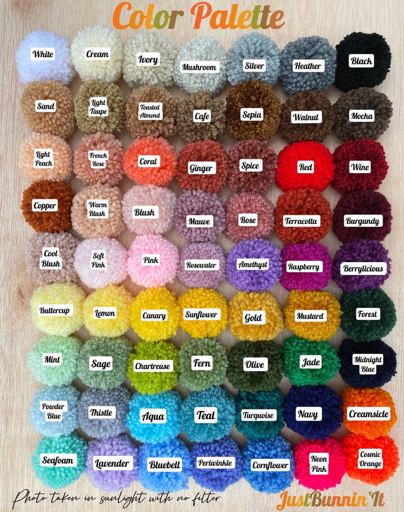May include: A color palette of 49 yarn pom-poms in various colors, arranged in a grid. The pom-poms are labeled with names like "White", "Cream", "Ivory", "Black", "Sand", "Light Taupe", "Toasted Almond", "Cafe", "Sepia", "Walnut", "Mocha", "Light Peach", "French Rose", "Coral", "Ginger", "Spice", "Red", "Wine", "Copper", "Warm Blush", "Blush", "Mauve", "Rose", "Terracotta", "Burgundy", "Cool Blush", "Soft Pink", "Pink", "Rosewater", "Amethyst", "Raspberry", "Berrylicious", "Buttercup", "Lemon", "Canary", "Sunflower", "Gold", "Mustard", "Forest", "Mint", "Sage", "Chartreuse", "Fern", "Olive", "Jade", "Midnight Blue", "Powder Blue", "Thistle", "Aqua", "Teal", "Turquoise", "Navy", "Creamsicle", "Seafoam", "Lavender", "Bluebell", "Periwinkle", "Cornflower", "Neon Pink", "Cosmic Orange". The image includes the text "Color Palette" and "Just Bunnin' It".
