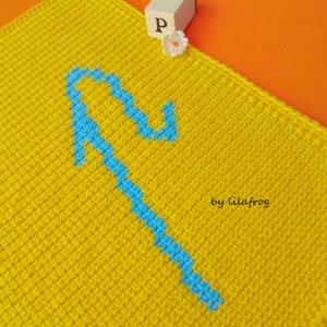 May include: A yellow crochet square with a blue arrow design. The text "by lilafrog" is in the bottom right corner.