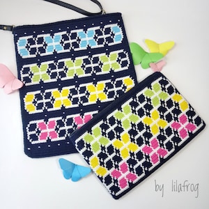 May include: Two crocheted bags with a butterfly design. The larger bag has a strap and is navy blue with white, yellow, pink, and light blue butterflies. The smaller bag is navy blue with white, yellow, green, and pink butterflies. The text "by lilafrog" is in the bottom right corner of the image.