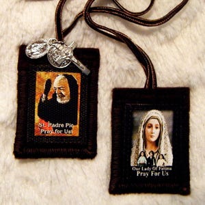 May include: Two brown fabric prayer cards with images of St. Padre Pio and Our Lady of Fatima. The cards have the text "St. Padre Pio Pray for Us" and "Our Lady of Fatima Pray for Us".