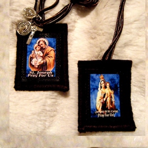 Puede incluir: Dos tarjetas de oración de tela marrón con imágenes de San José y Nuestra Señora del Monte Carmelo. Cada tarjeta tiene un cordón marrón y el texto "Reza por nosotros".