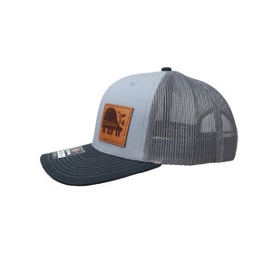 May include: A gray and navy blue trucker hat with a brown leather patch featuring the word "Fidelity" and a piano silhouette.