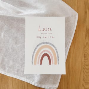 Può includere: Biglietto di annuncio di nascita con il nome "Luise" in scrittura bordeaux. Il biglietto presenta un arcobaleno ad acquerello nei toni del pesca, rosa e marrone. Il biglietto include anche la data, il peso (3570g), l'altezza (59cm) e l'ora di nascita.