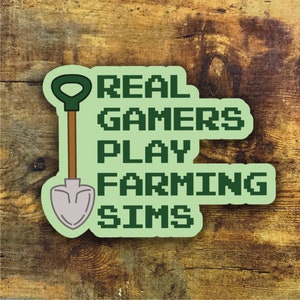 May include: Green and white sticker with a pixelated shovel and the text "REAL GAMERS PLAY FARMING SIMS".