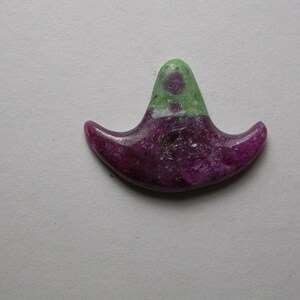 May include: A crescent-shaped pendant made of green and pink gemstone. The pendant has a smooth, polished surface and a unique, abstract design.