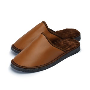 May include: A pair of brown leather slippers with a soft, brown fur lining. The slippers have a black rubber sole.