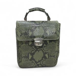 Puede incluir: Bolso de mano verde y negro con estampado de piel de serpiente, con asa superior y cierre plateado. El bolso tiene forma rectangular con cierre de solapa. El asa está sujeta con herrajes metálicos oscuros.
