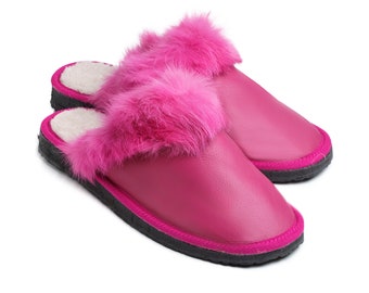 May include: A pair of pink fluffy slippers with a black trim. The slippers are made of leather and have a soft, fluffy lining.