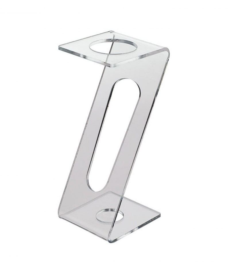 May include: Clear acrylic display stand with two circular openings. The stand is shaped like a Z and has a rectangular base.
