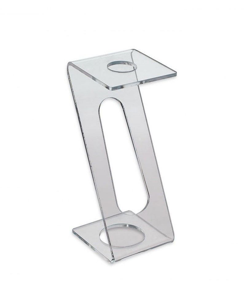 May include: Clear acrylic stand with two circular openings for displaying items. The stand has a Z-shaped design and a square base.