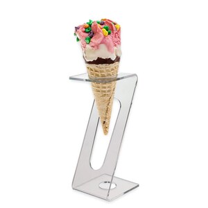 May include: A clear acrylic ice cream cone holder with a single ice cream cone with pink and white ice cream and colorful sprinkles.