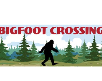 May include: A red and white sign with the text "BIGFOOT CROSSING" in red letters. A black silhouette of Bigfoot walking through a green forest is in the center of the sign.