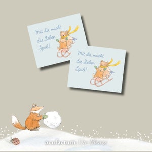 Könnte beinhalten: Zwei Karten mit blauem Hintergrund und weißem Rand. Die Karten zeigen eine Cartoon-Illustration von zwei Bären auf einem Schlitten. Der Text auf den Karten lautet "Mit dir macht das Leben Spaß!"