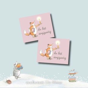 Può includere: Due biglietti quadrati rosa con un fumetto di una volpe che tiene in mano una candela e un libro. Il testo sui biglietti recita "du bist einzigartig". Un tasso porta libri sullo sfondo. Il nome dell'artista è in basso.