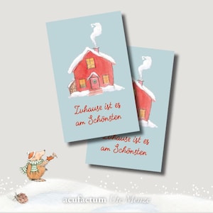 Könnte beinhalten: Ein rotes Haus mit einem weißen Dach und Rauch aus dem Schornstein. Das Haus ist von Schnee umgeben und der Text "Zuhause ist es am Schönsten" steht unter dem Haus.