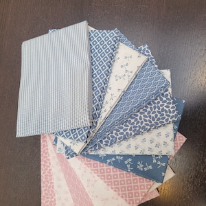 May include: A stack of 12 fabric squares in shades of blue and pink with various patterns, including geometric designs, dragonflies, and floral motifs.