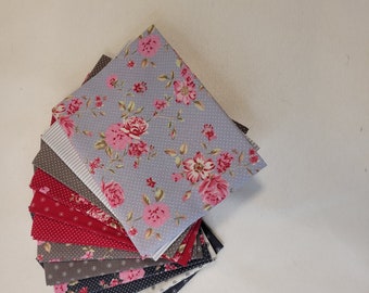 Pode incluir: Uma pilha de quadrados de tecido em vários padrões, incluindo floral, de bolinhas e listrado. O quadrado superior é um tecido azul claro com um padrão floral rosa e branco.