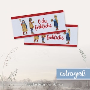 May include: Two white fabric labels with red borders and a Christmas scene. The labels feature the text "O du fröhliche" and three figures carrying gifts. The labels are extra large.