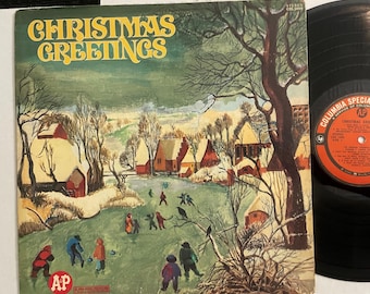 May include: Vintage Christmas album cover with the words "Christmas Greetings" in gold lettering. The cover art depicts a winter scene with people ice skating, snow-covered houses, and trees. A black vinyl record is visible on the right.